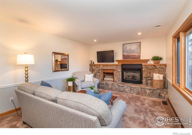 carpeted living room with a stone fireplace