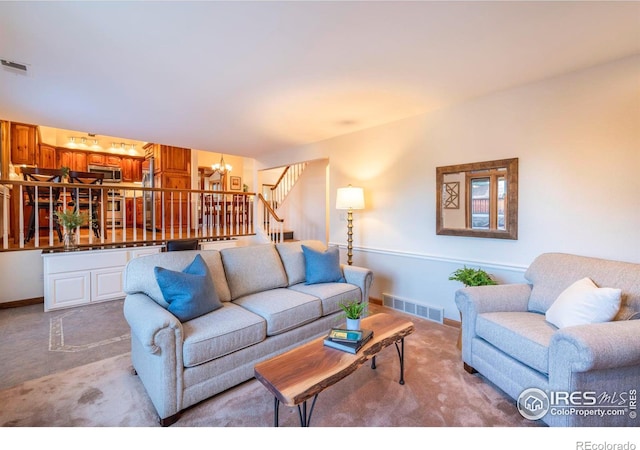 carpeted living room featuring an inviting chandelier