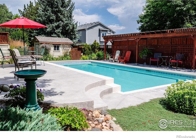 view of pool featuring a patio area, a pergola, and an outbuilding