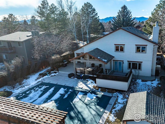 snow covered property with a deck with mountain view