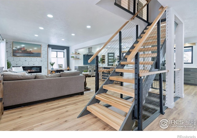 stairway featuring a large fireplace and wood-type flooring