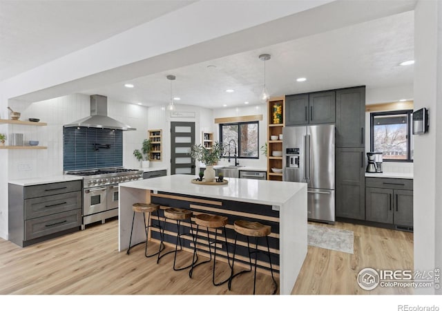 kitchen with high end appliances, wall chimney exhaust hood, open shelves, and light countertops