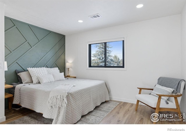 bedroom with baseboards, wood finished floors, visible vents, and recessed lighting