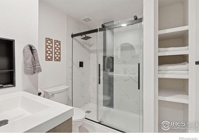 bathroom with toilet, a marble finish shower, visible vents, and vanity