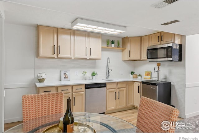 kitchen with stainless steel appliances, visible vents, a sink, and light brown cabinetry