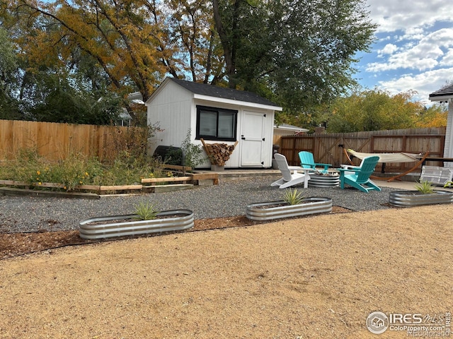 view of outdoor structure with an outdoor fire pit, a fenced backyard, and an outdoor structure