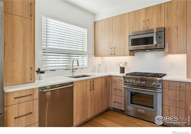 kitchen featuring tasteful backsplash, sink, light hardwood / wood-style flooring, stainless steel appliances, and light brown cabinets