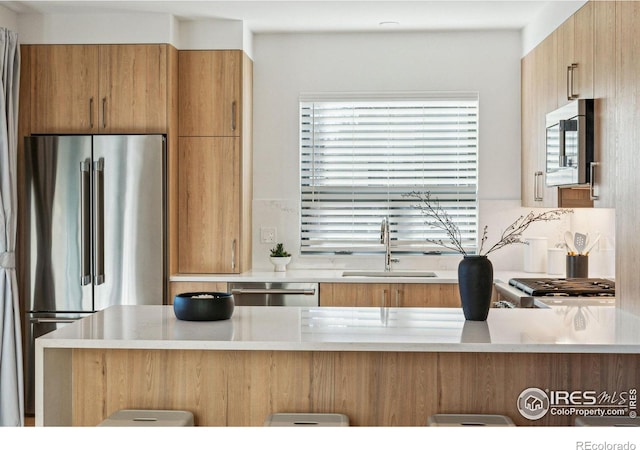 kitchen with sink, decorative backsplash, kitchen peninsula, and appliances with stainless steel finishes