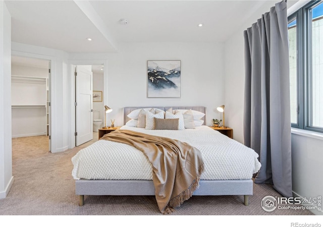 carpeted bedroom featuring a walk in closet, a closet, and multiple windows