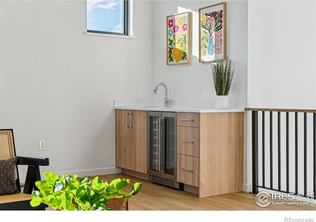 bar with light hardwood / wood-style floors, sink, and wine cooler