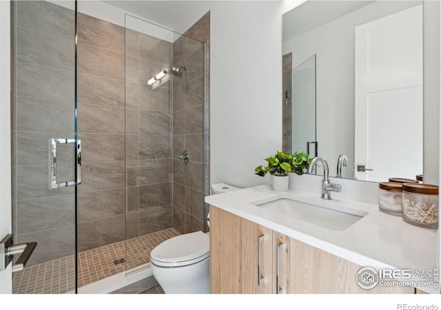 bathroom featuring a shower with shower door, toilet, and vanity