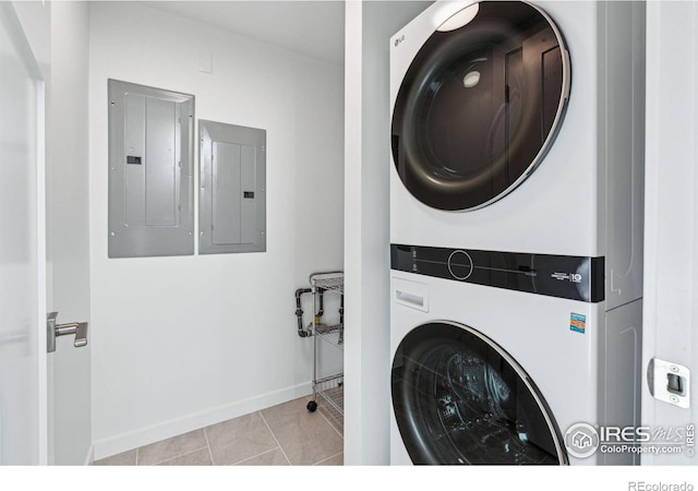 laundry room with electric panel, light tile patterned floors, and stacked washing maching and dryer