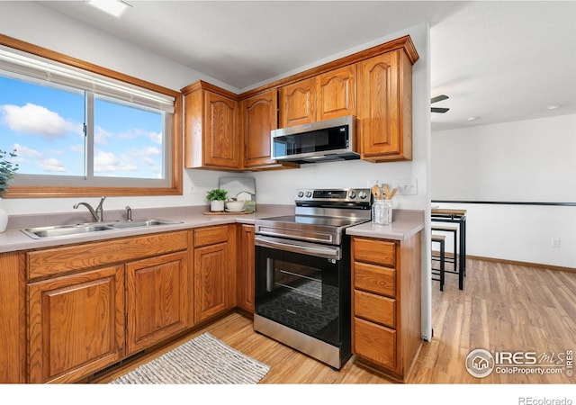 kitchen with stainless steel appliances, light wood-type flooring, and sink