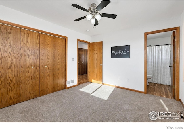 unfurnished bedroom with ceiling fan, a closet, ensuite bath, and carpet floors