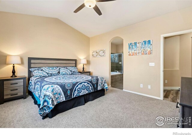 bedroom featuring ceiling fan, vaulted ceiling, ensuite bathroom, and carpet flooring