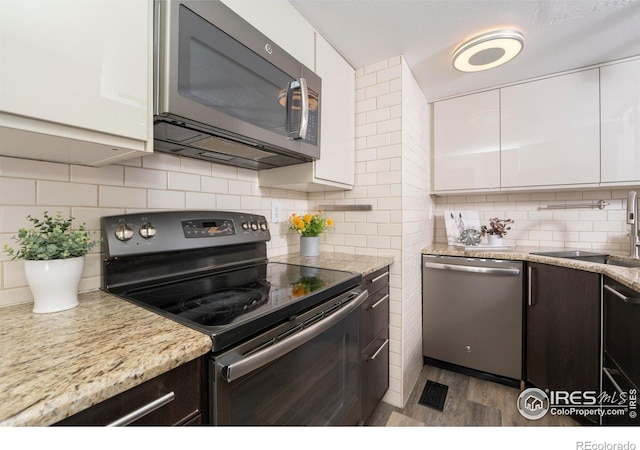 kitchen featuring sink, white cabinets, decorative backsplash, and appliances with stainless steel finishes