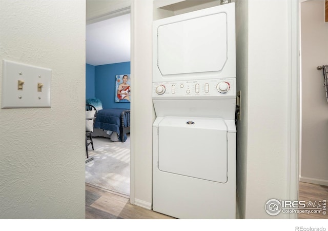 washroom with light hardwood / wood-style floors and stacked washer and clothes dryer