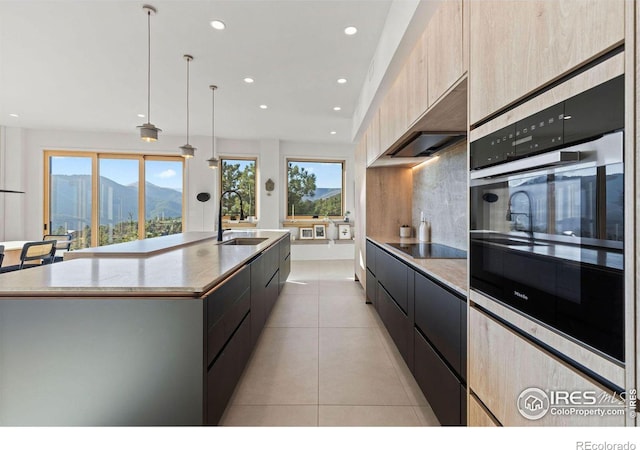 kitchen with a spacious island, sink, hanging light fixtures, a mountain view, and oven