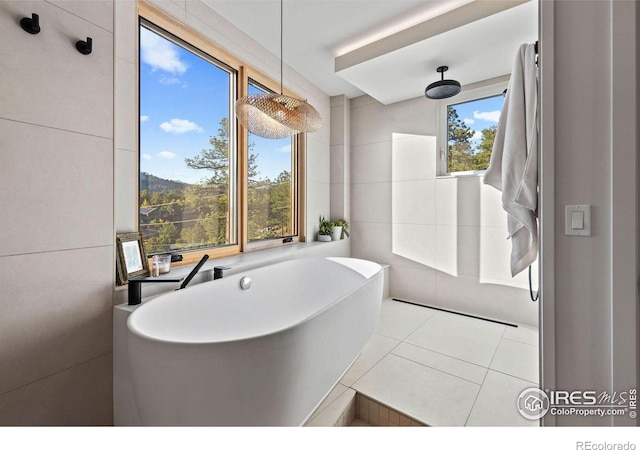 bathroom featuring tile walls, tile patterned floors, and a tub to relax in