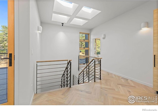 hallway with light parquet floors and a skylight