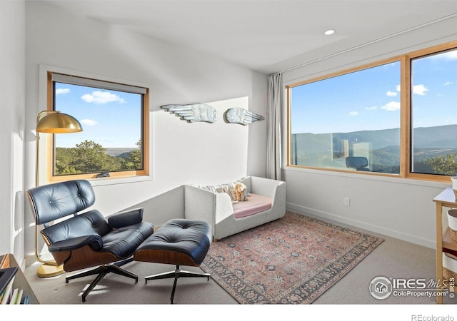 sitting room with a mountain view, plenty of natural light, and carpet flooring