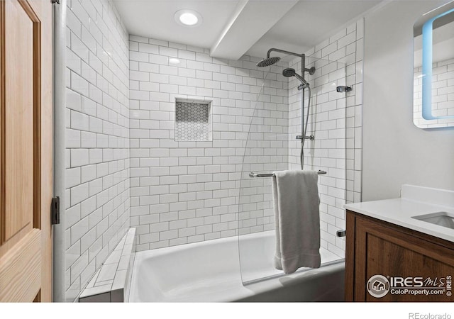 bathroom featuring tiled shower / bath combo and vanity