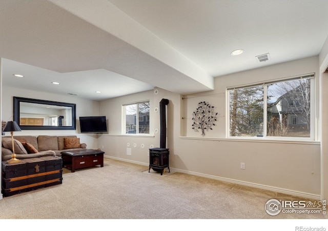 living room featuring visible vents, baseboards, carpet, recessed lighting, and a wood stove