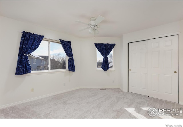 unfurnished bedroom with visible vents, a closet, carpet floors, baseboards, and ceiling fan