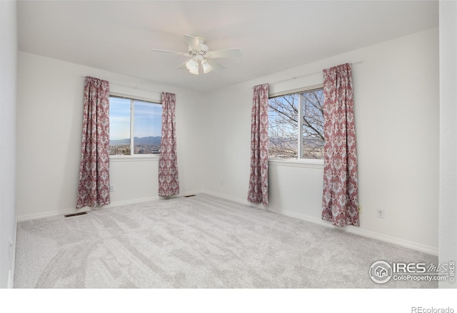 spare room featuring carpet flooring, visible vents, baseboards, and a ceiling fan