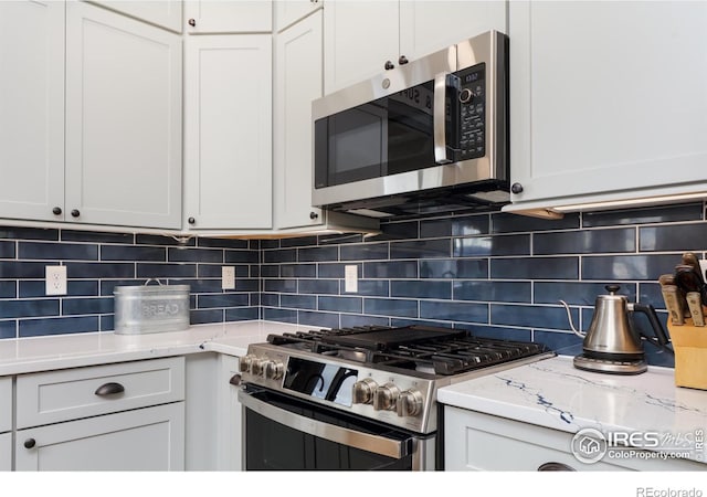 kitchen featuring stainless steel appliances, decorative backsplash, and white cabinetry