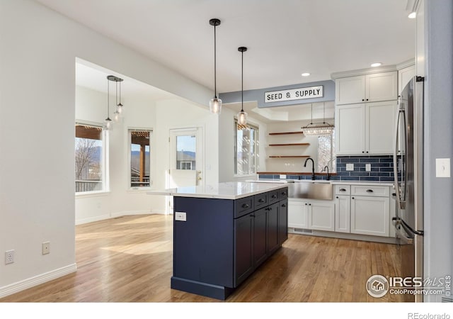 kitchen with backsplash, light wood finished floors, white cabinetry, and freestanding refrigerator