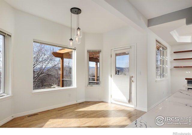 unfurnished dining area with baseboards, visible vents, a wealth of natural light, and light wood-type flooring