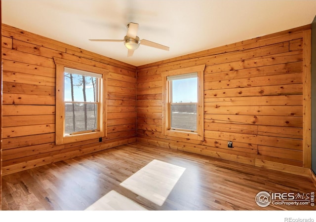 spare room with plenty of natural light, wood walls, and light hardwood / wood-style flooring