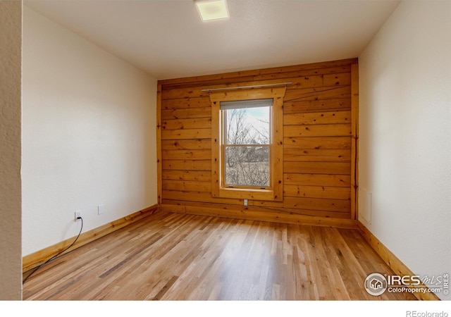 spare room featuring light wood-type flooring and wooden walls