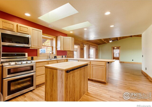 kitchen with stainless steel appliances, a center island, sink, and light brown cabinetry