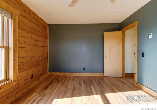 spare room featuring light hardwood / wood-style flooring and wood walls