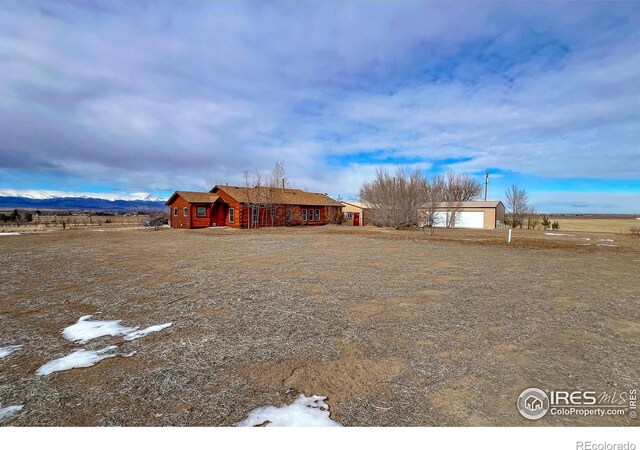 view of yard featuring a garage, a mountain view, and a rural view