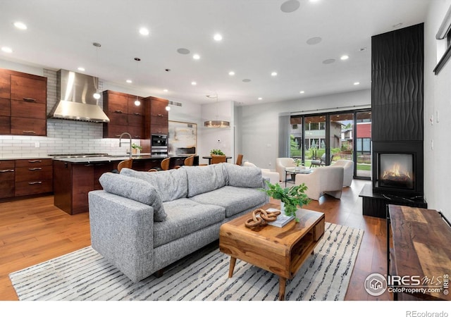 living room featuring a multi sided fireplace, light hardwood / wood-style floors, and sink