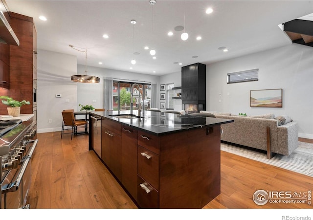 kitchen featuring stainless steel appliances, a center island with sink, sink, and light hardwood / wood-style floors