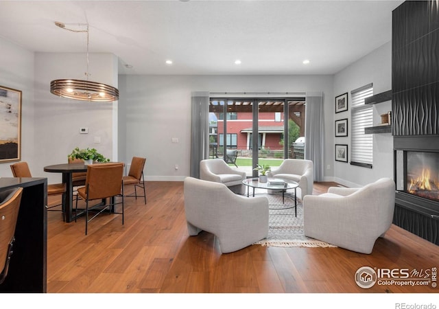 living room featuring an inviting chandelier, plenty of natural light, a fireplace, and wood-type flooring