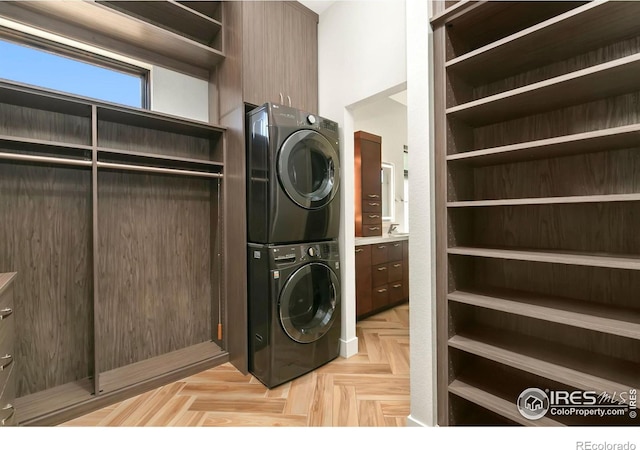 laundry area with stacked washer and dryer and light parquet floors