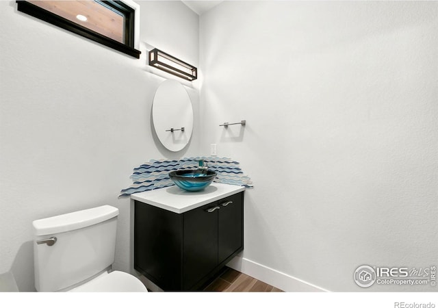 bathroom featuring toilet, wood-type flooring, and vanity