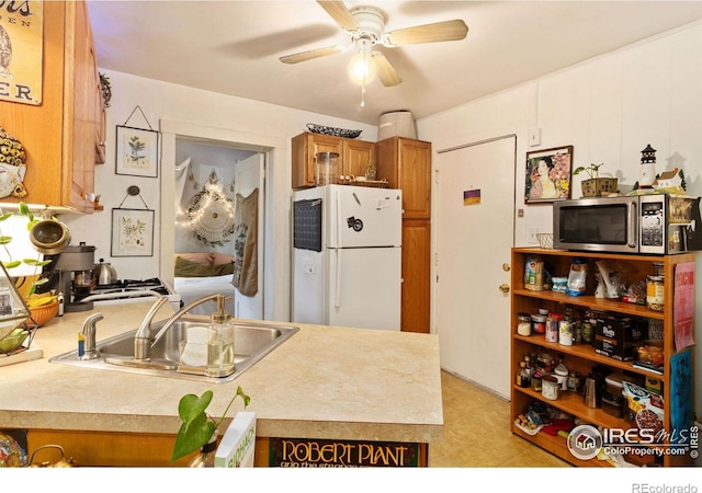 kitchen featuring sink, ceiling fan, white fridge, and kitchen peninsula