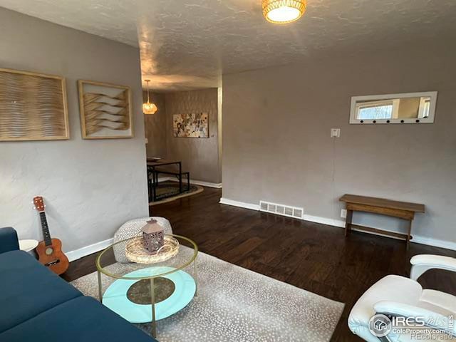 living room with dark wood-type flooring and a textured ceiling