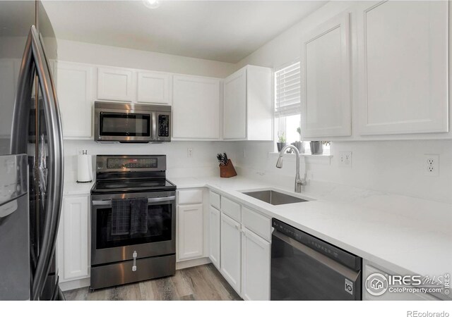 kitchen featuring stainless steel appliances, white cabinetry, light hardwood / wood-style floors, and sink