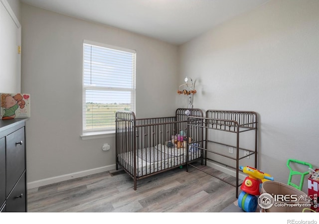 bedroom featuring light wood-type flooring and a crib