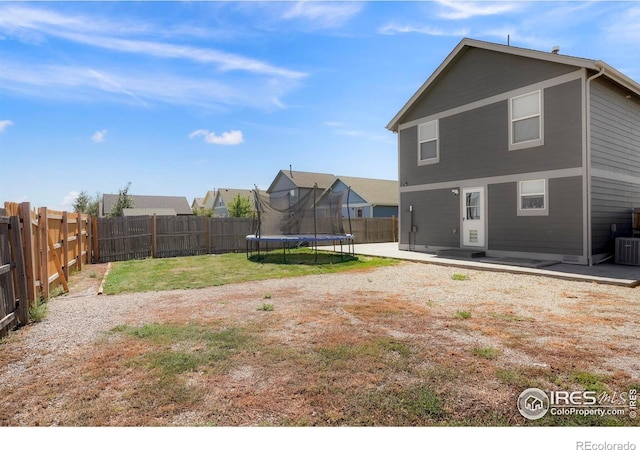 rear view of house with a lawn, a patio area, and a trampoline