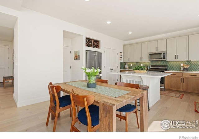 kitchen featuring a kitchen island, appliances with stainless steel finishes, light hardwood / wood-style floors, and tasteful backsplash