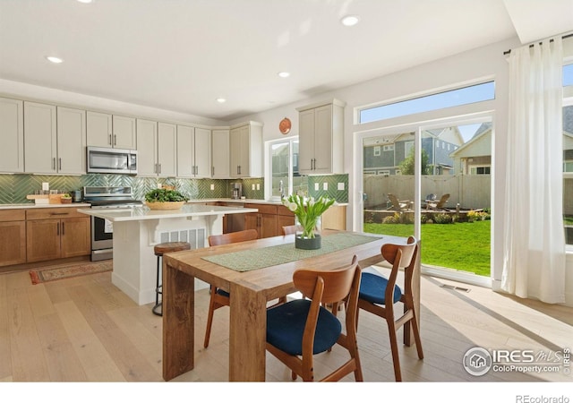 kitchen with a kitchen island, appliances with stainless steel finishes, light hardwood / wood-style flooring, and tasteful backsplash