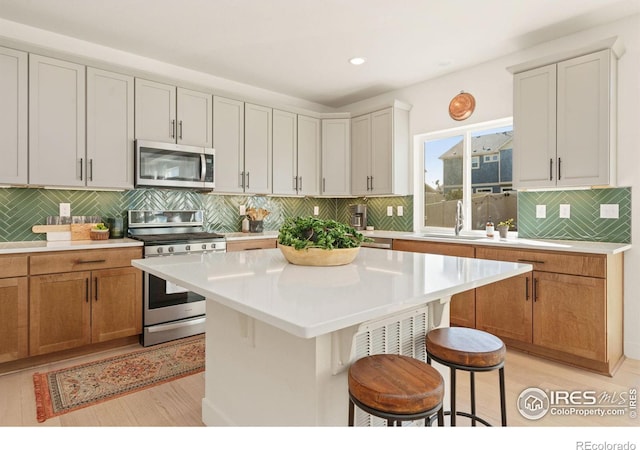 kitchen featuring stainless steel appliances, sink, white cabinets, a center island, and a breakfast bar area